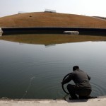 A security guard tries to find the puncture in the inner-tube of his bicycle tyre by immersing it in the former course for the kayaking competition of the 2008 Beijing Olympic Games, on the outskirts of Beijing